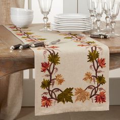 a table topped with plates and glasses next to a wooden table covered in fall leaves