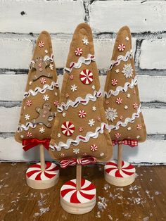 three christmas trees made out of cardboard and decorated with candy canes on top of a wooden table