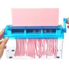 two hands are holding a pink and blue plastic box with wires in it, while another hand holds the lid