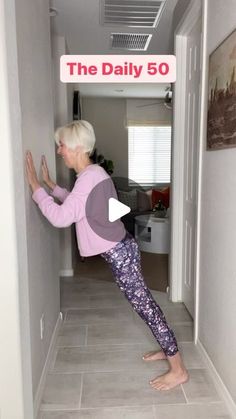 an older woman is doing yoga in the hallway