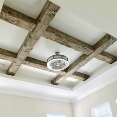 a ceiling fan mounted to the ceiling in a room with exposed wood beams and white walls