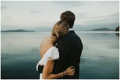 a man and woman standing next to each other near the water