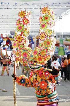 an elaborately decorated animal holding a stick in its mouth at a fair or festival