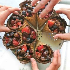 four people holding cones filled with fruit and chocolate