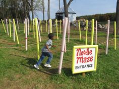 a little boy standing in front of a sign that says noodle maze entrance on it