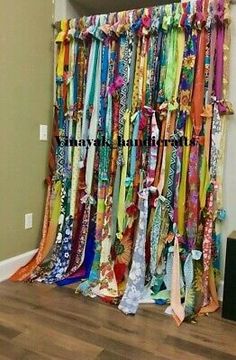 an assortment of colorful ties hanging on a wall in front of a window with the curtains pulled back