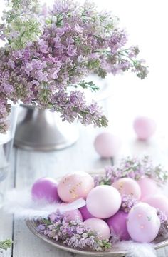 a plate with eggs and flowers on it next to a glass vase filled with lavender