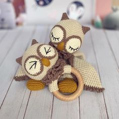 two crocheted owls sitting next to each other on a white table with a wooden ring