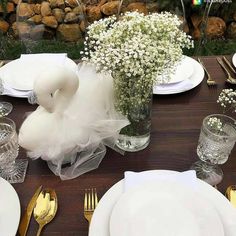 the table is set with white plates, silverware and baby's breath flowers