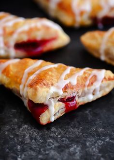 croissants with white icing on them sitting on a black surface