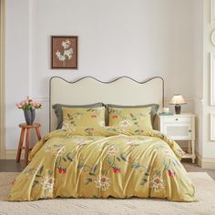 a bed with yellow comforter and pillows in a room next to a white dresser