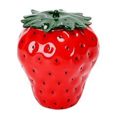 a red ceramic strawberry with green leaves on it's top and eyes painted black