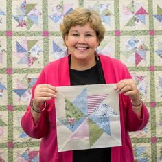 a woman holding up a piece of quilt