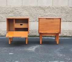 two wooden nightstands sitting next to each other in front of a brick wall and cement floor