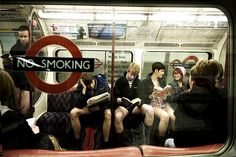 there are many people sitting on the subway train and one person is holding a book