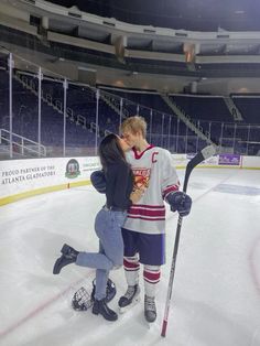 a man and woman standing on top of an ice hockey rink holding onto each other