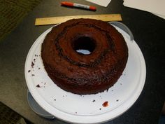 a chocolate cake sitting on top of a white plate next to a knife and ruler