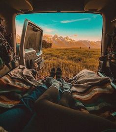 a person laying in the back of a truck with their feet up on a blanket