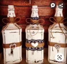 three white painted bottles with hearts tied to them