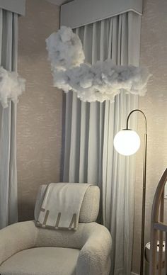 a white chair sitting next to a window with clouds hanging from it's ceiling