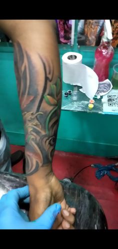 a person getting a tattoo done on their arm and leg in a barbershop