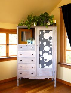 a white cabinet with flowers on it in a room next to a window and wooden floors