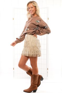 Saddle up and make a stylish statement with the Brielle Taupe Leather Fringe Mini Skirt ! This skirt is rodeo-ready with its taupe faux leather material, zip closure, and playful fringe detailing that cascades all the way down. Pair it with your favorite boots and a fun top for a look that's both chic and Western-inspired, perfect for any outing that calls for a touch of flair.   Features:   Bold taupe faux leather material for a sleek and edgy look.  Convenient zip closure for easy wearability. Fringe Mini Skirt, Jumper Denim, Sequined Sweatshirt, Baseball Outfit, Taupe Leather, Graphic Tee Dress, Favorite Boots, Edgy Look, Maxi Dresses Casual