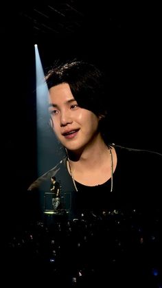 a man standing in front of a microphone on top of a stage with lights behind him