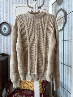 This sweater by Sun Valley is made from 100 per cent acrylic in cream/off white and camel beige and features the cable stitch in the front. Marked size large. The measurements, taken with the sweater lying flat, are: shoulder to shoulder, 21 inches; armpit to armpit, 24 inches; sleeves, 27 inches; length, 27 inches; bottom edge, 15 inches (with stretchy ribbing). In very good condition. Neutral Cable Knit Sweater For Winter, Winter Cable Knit Pattern In Cream, Beige Cable Knit Pattern For Winter, Classic Chunky Knit Cream Sweater, Cream Chunky Knit Classic Sweater, Winter Beige Cable Knit Pattern, Classic Beige Cable Knit Sweater, Classic Cream Chunky Knit Sweater, Beige Knitted Retro Sweater