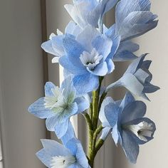 a vase with blue flowers in it sitting on a window sill next to a wall