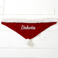 a red dog bandana with the word duffy on it's side hanging from a white brick wall