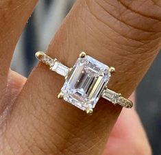 a woman's engagement ring with an emerald and baguettes