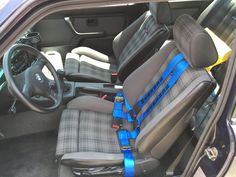 the interior of a car with grey seats and blue straps on it's armrests