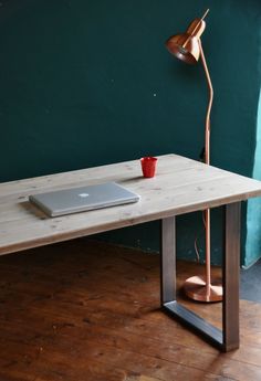 a wooden table with a laptop on it and a lamp in the corner next to it