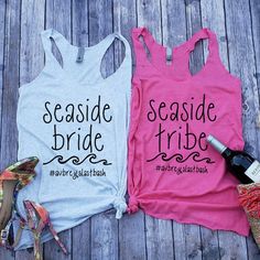 two shirts that say seaside bride and seaside tribe on the front, one has a bottle of wine next to it