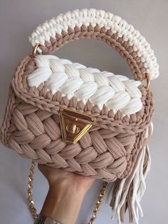 a hand holding a beige and white purse