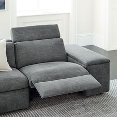 a gray couch sitting on top of a rug next to a window