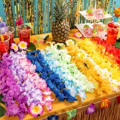 a table topped with lots of flowers and pineapples next to a rainbow flag