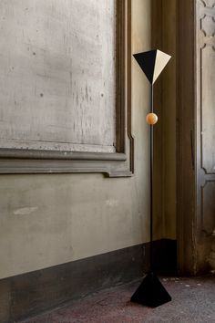 a black and white floor lamp sitting in front of a window next to a door