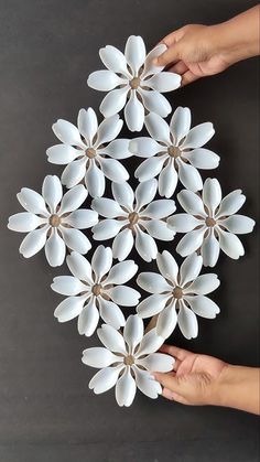 two hands are holding white paper flowers