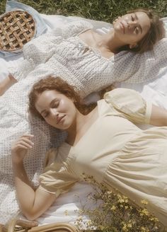 two women laying on a blanket in the grass next to each other with pies