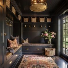 a room with a bench, rug and baskets on the wall next to it's windows