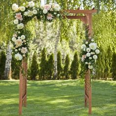 an outdoor wedding ceremony setup with flowers and greenery on the arch, surrounded by trees