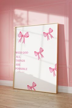 a pink room with a white framed poster on the wall and some pink bows tied to it