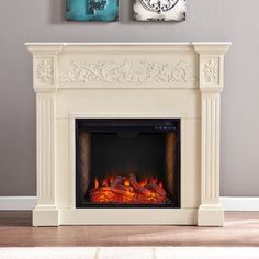 a fireplace with two paintings on the wall above it and a fire place in front of it