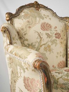 an ornately decorated chair with gold trimmings and floral upholstered fabric