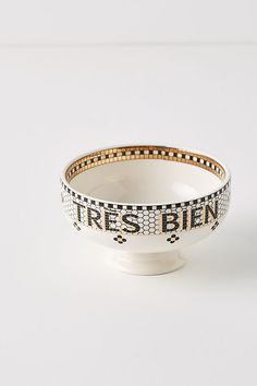 a white bowl with black and gold trimmings on the rim that says tres bien