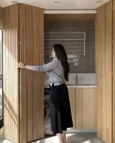 a woman standing in front of a washer next to a window with blinds on it