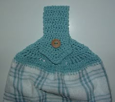 a blue and white crocheted bag hanging on the wall with a button in it