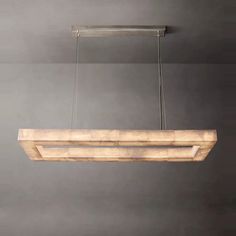 a wooden light fixture hanging from the ceiling in a room with gray walls and flooring